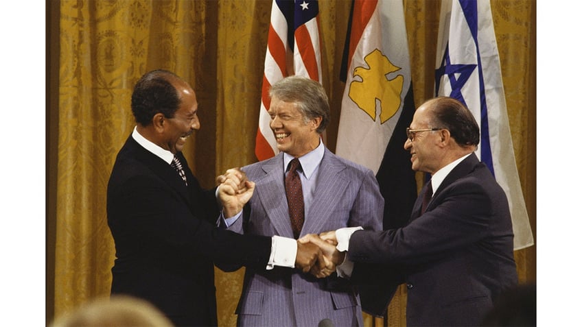 Egyptian President Anwar Sadat, U.S. President Jimmy Carter, and Israeli Prime Minister Menachem Begin join hands after the Camp David Accords September 18, 1978 in the East Room of the White House in Washington, DC. 