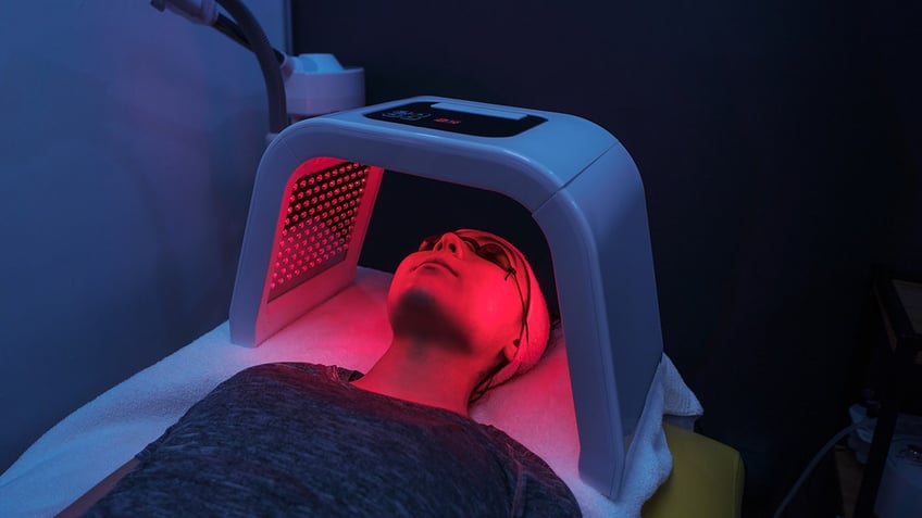 Woman doing red-light therapy over her head.