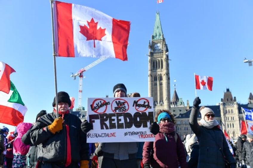 A protester holds up a sign condemning the vaccine mandates introduced by Canadian Prime M