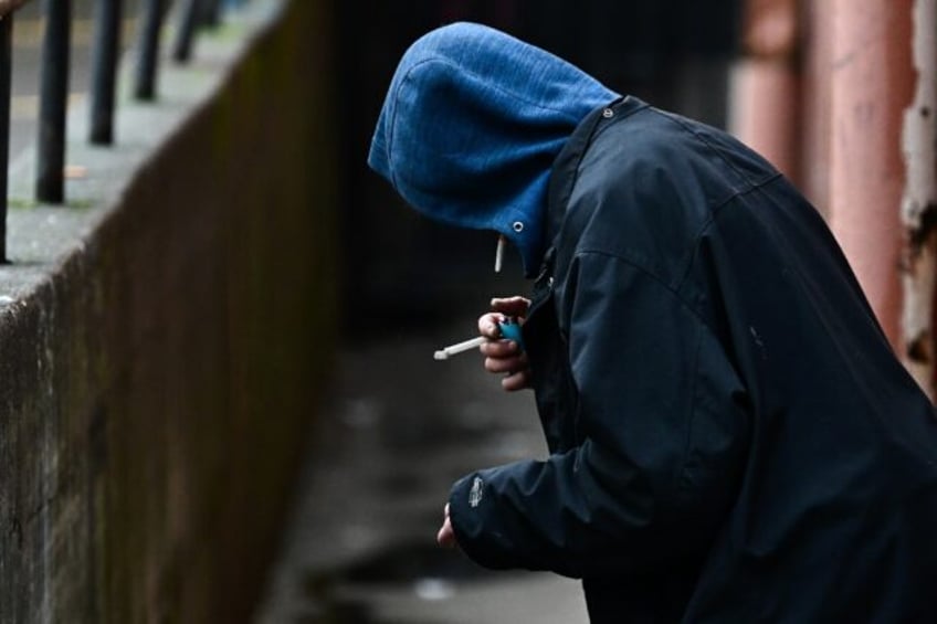 A person holds a lighter in an alleyway while smoking in the US state of Oregan in 2024