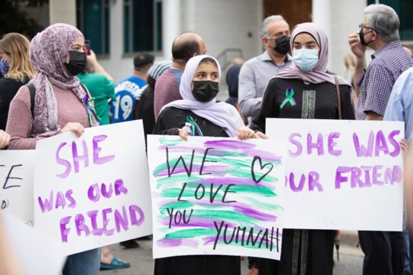 Friends of late Yumnah Afzaal hold placards as they gather prior to a vigil her and her fa