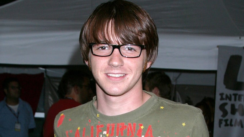 Drake Bell wearing a green shirt and glasses in 2004