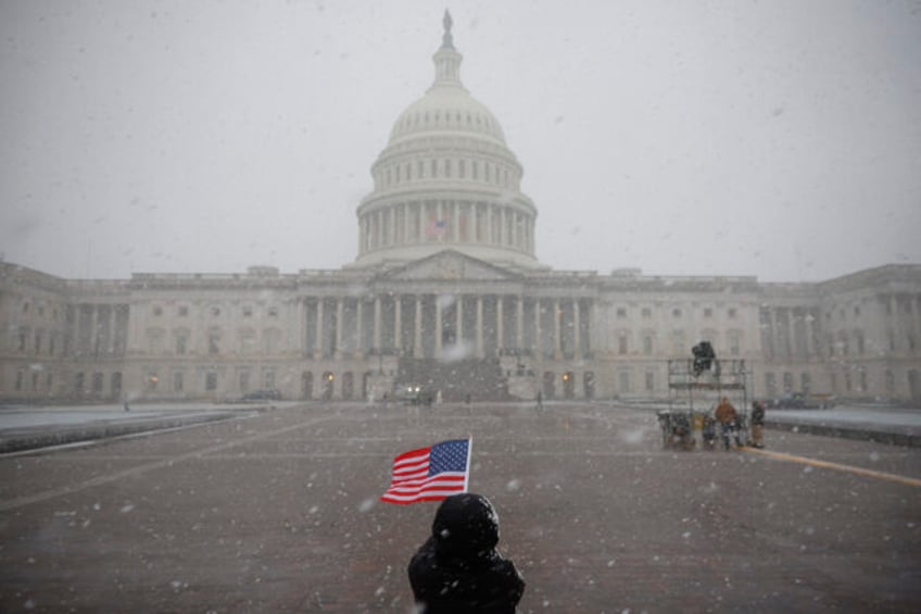 WASHINGTON, DC - JANUARY 19: An American flag is held in the snow outside the U.S. Capitol