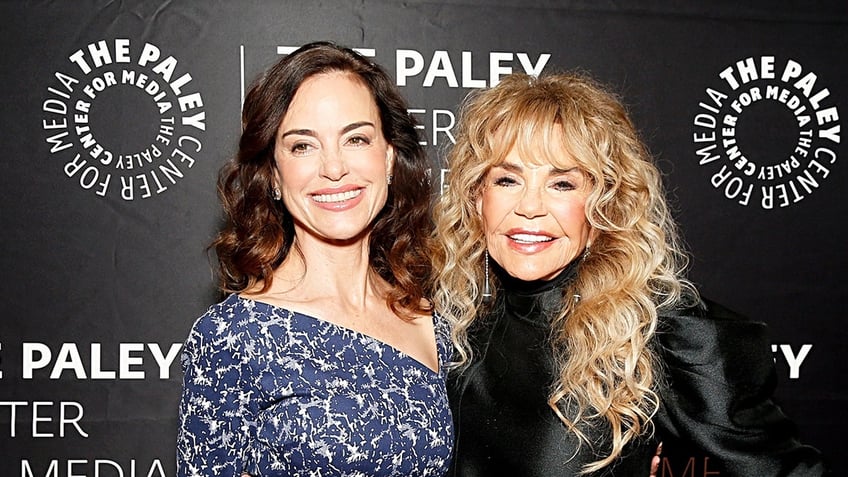 Jennifer Grant in a blue and white dress smiling next to her mother Dyan Cannon in a black outfit