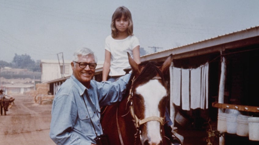 Jennifer Grant on top of a horse next to a smiling Cary Grant