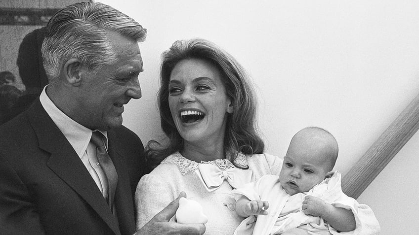 Cary Grant and Dyan Cannon laughing with each other as Dyan Cannon holds a baby Jennifer Grant