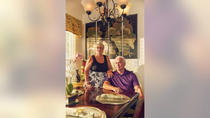 George Anthony sitting down in a lit living room with Cindy Anthony placing her hand on his shoulder