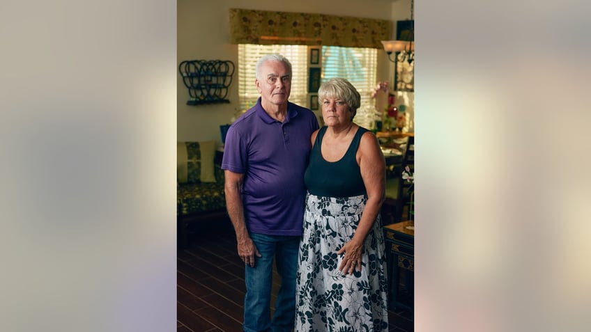 George and Cindy Anthony standing next to each other and looking serious in a low lit room