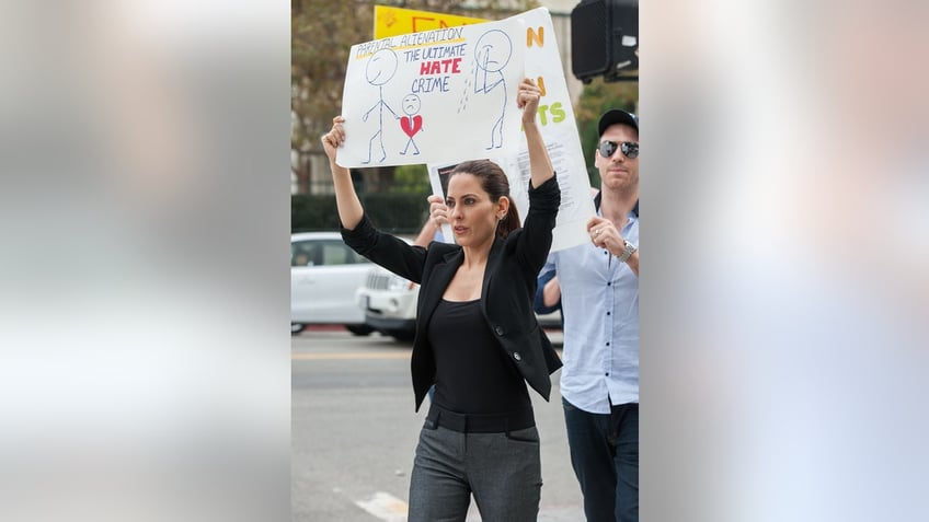 Kerri Kasem holding a sign and marching outdoors.