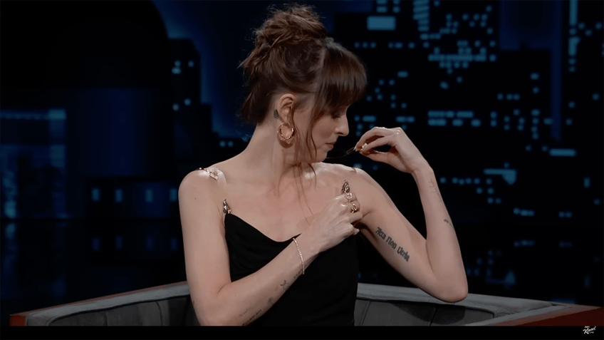 Dakota Johnson inspects the damage to her black dress on 'Jimmy Kimmel Live!'