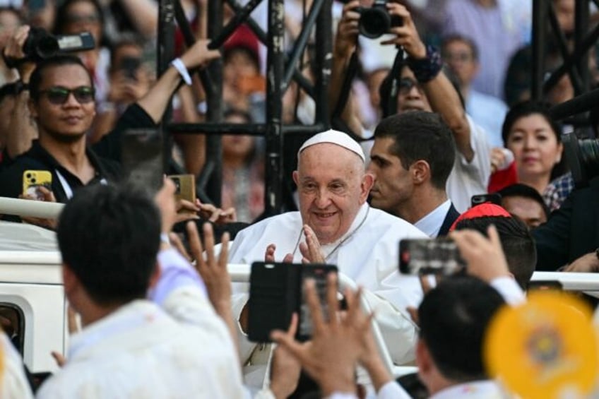 Pope Francis waves as he arrives to attend the holy mass in Indonesian capital Jakarta