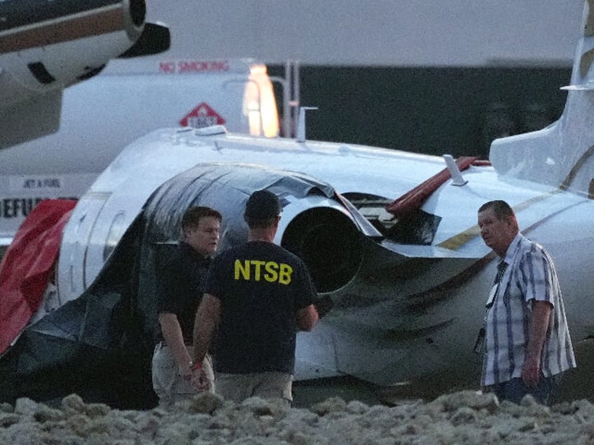 Investigators look at a crashed Learjet at Scottsdale Airport after it collided with a par