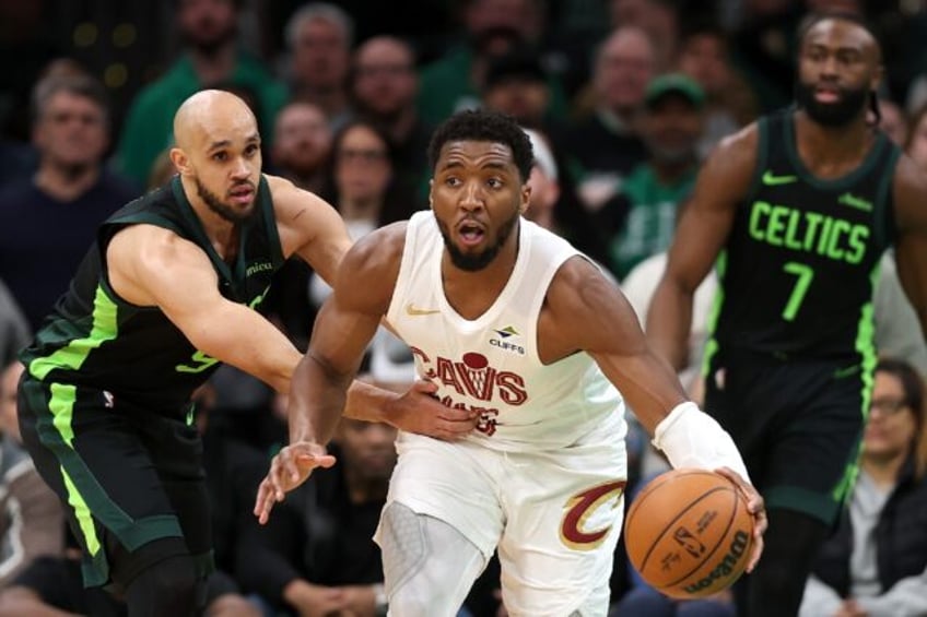 Donovan Mitchell of the Cleveland Cavaliers drives past Derrick White in the Cavs' NBA vic