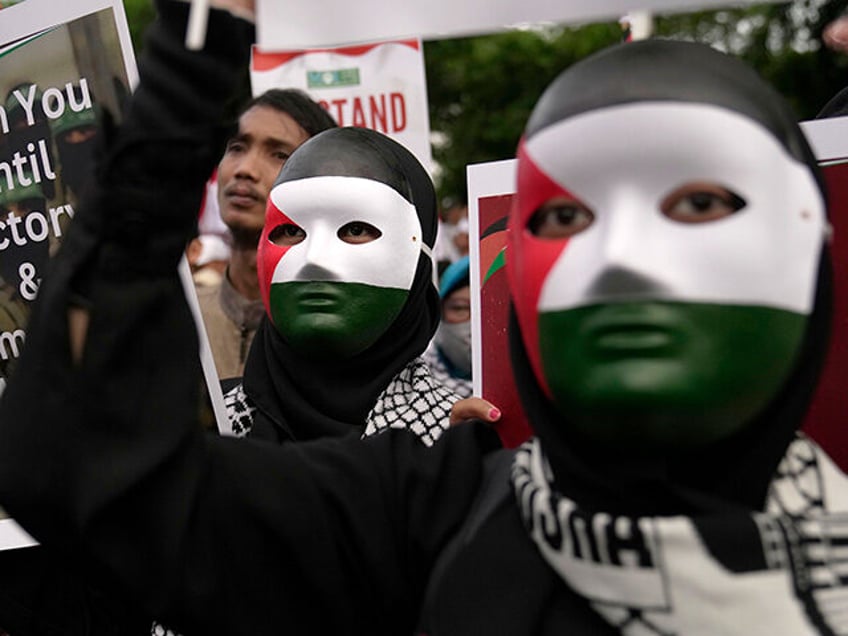 Protesters wearing masks with the colors of Palestinian flag hold posters during a rally in support of the Palestinians outside the U.S. Embassy in Jakarta, Indonesia, Saturday, Jan. 13, 2024. Thousands of people attended the rally ahead of the 100th day since the war between Israel and Hamas in Gaza. …