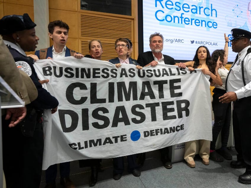 Climate protestors stand on stage after interrupting a speech by Federal Reserve Chairman