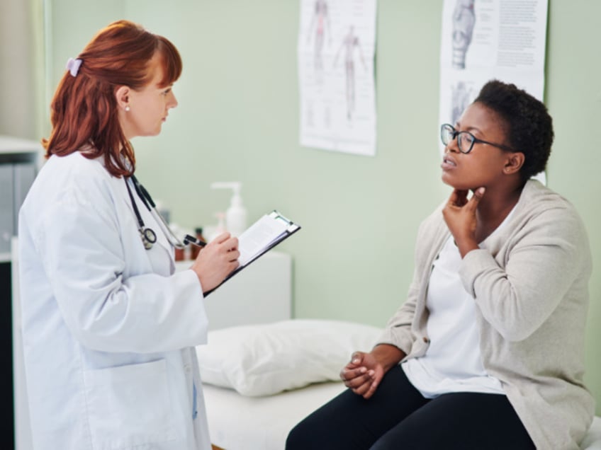 A doctor examines a woman who has throat issues (Stock photo via Getty).