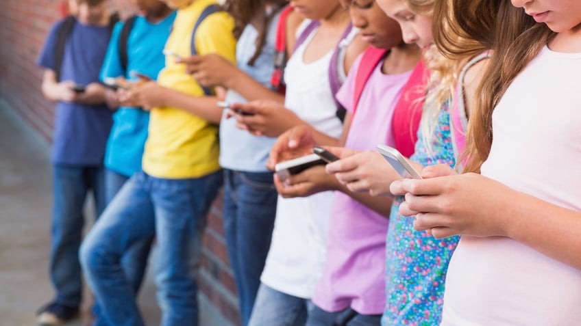 young kids on phones outside school