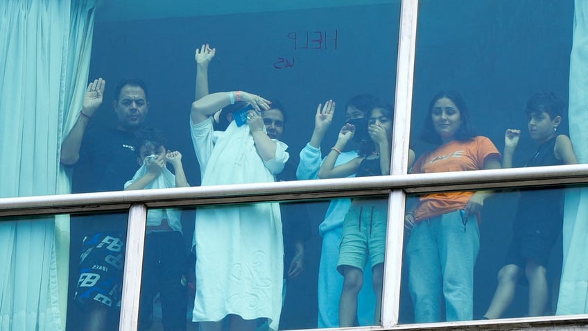 migrants waving from hotel window