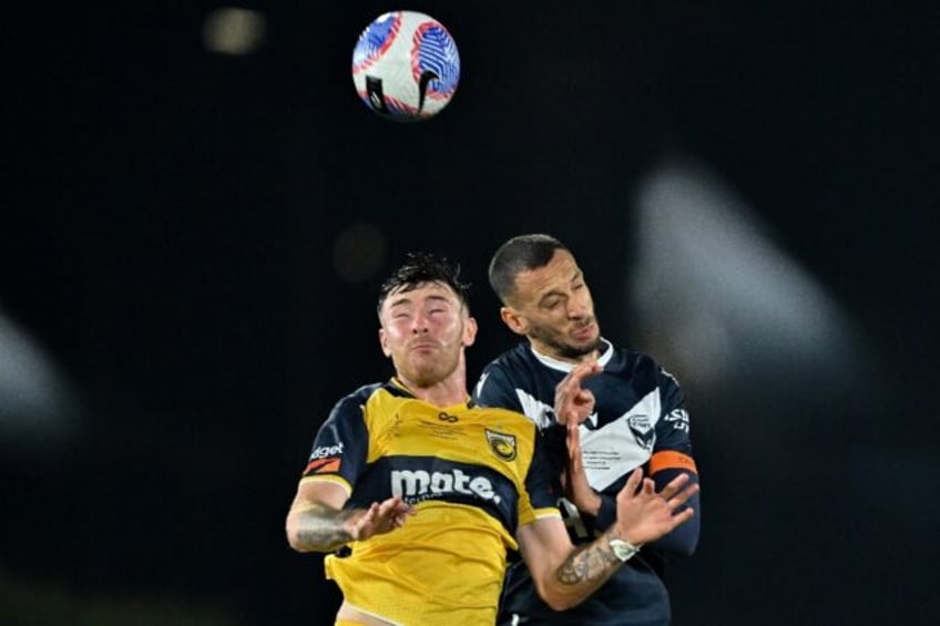 Central Coast Mariners' Bradley Tapp and Melbourne Victory's Nishan Velupillay challenge f