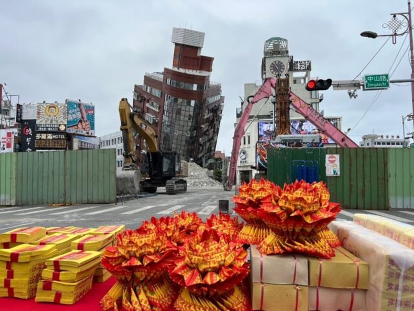 Paper money is placed on a table as an offering before demolition work begins on a precari