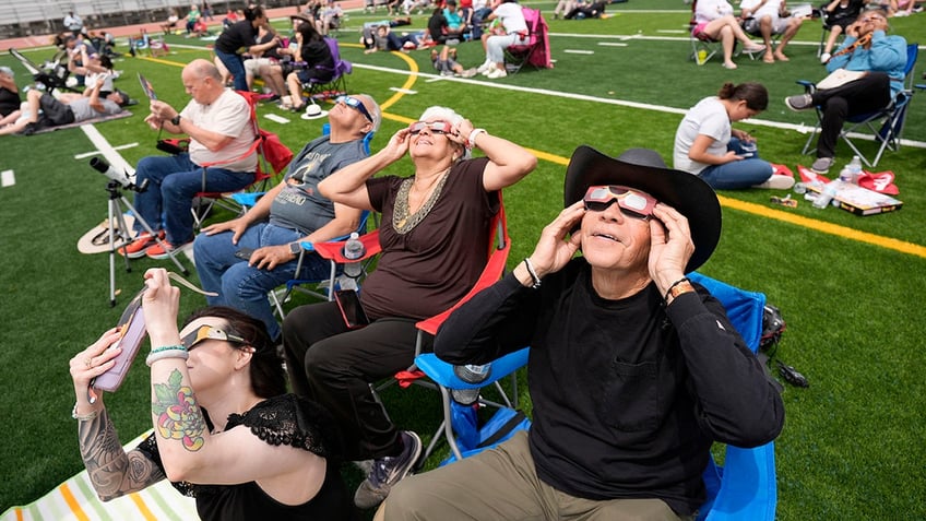 People watch as the moon partially covers the sun during a total solar eclipse in Eagle Pass, Texas