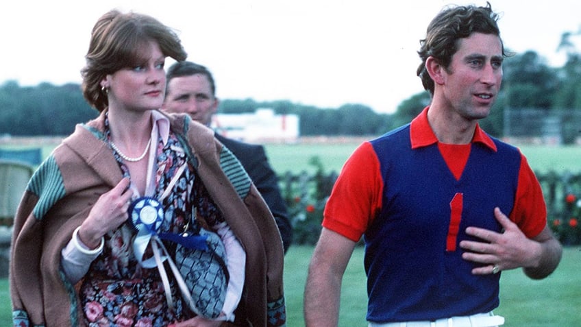 Prince Charles in a blue and red polo shirt walking next to Lady Sarah Spencer in a brightly printed dress