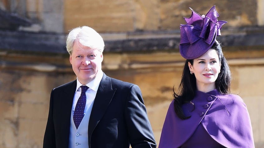 Charles Spencer in a suit walking alongside Karen Spencer in a purple dress and matching hat.