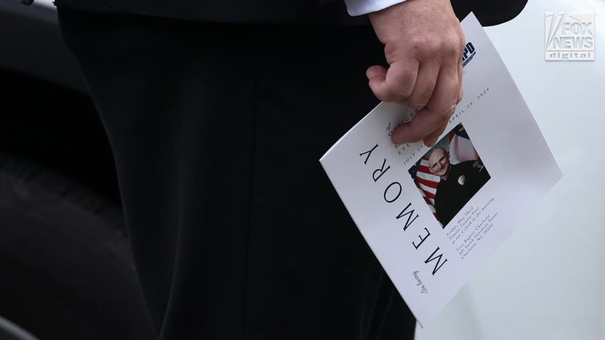 Close-up of a person's hand holding the program for the memorial