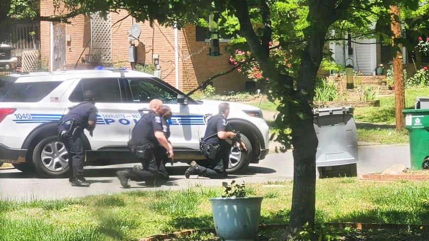 Charlotte officer crouch behind a police vehicle on Galway Drive