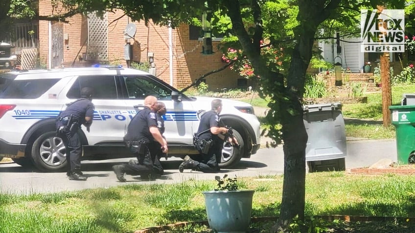 Charlotte officer crouch behind a police vehicle on Galway Drive