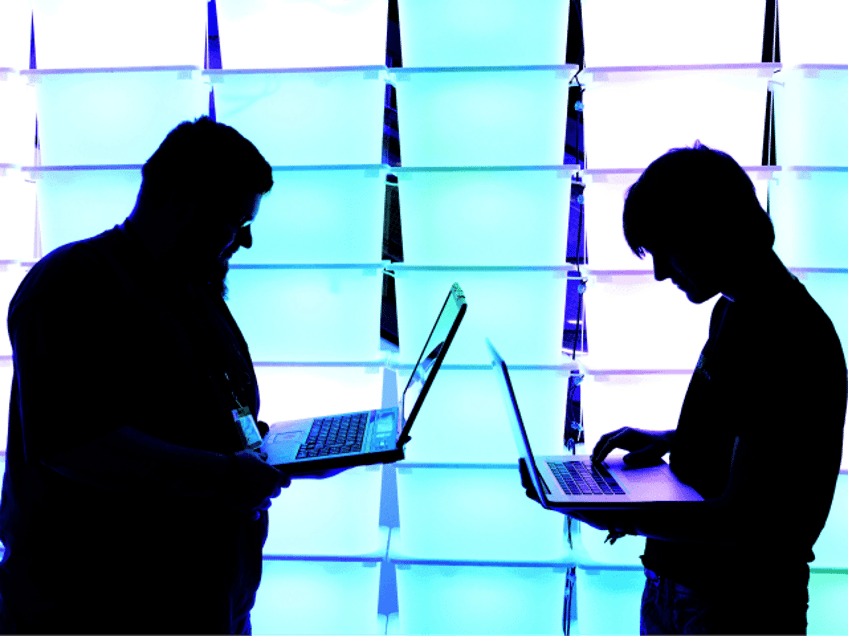 Participant hold their laptops in front of an illuminated wall at the annual Chaos Compute