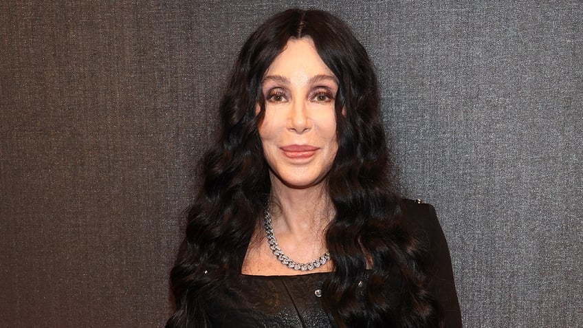 Cher purses her lips on the carpet in a sparkly black outfit