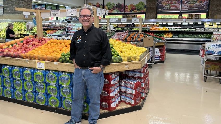 grocery store owner in front of produce display