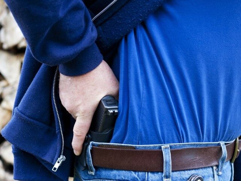 A man drawing his modern polymer (Glock) .45 caliber pistol from an IWB (inside the waistb