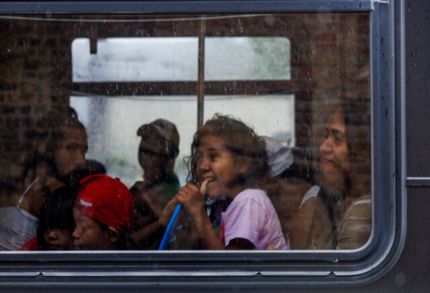 Migrants look out the window as they ride a CTA bus leaving the High Ridge YMCA shelter to be transferred to Daley College on June 13, 2023.