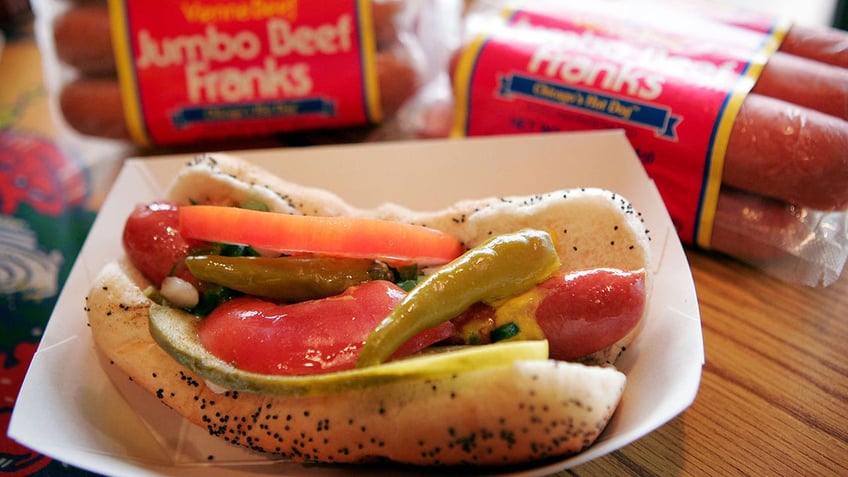 A Chicago style hot dog in front of packs of hot dogs.