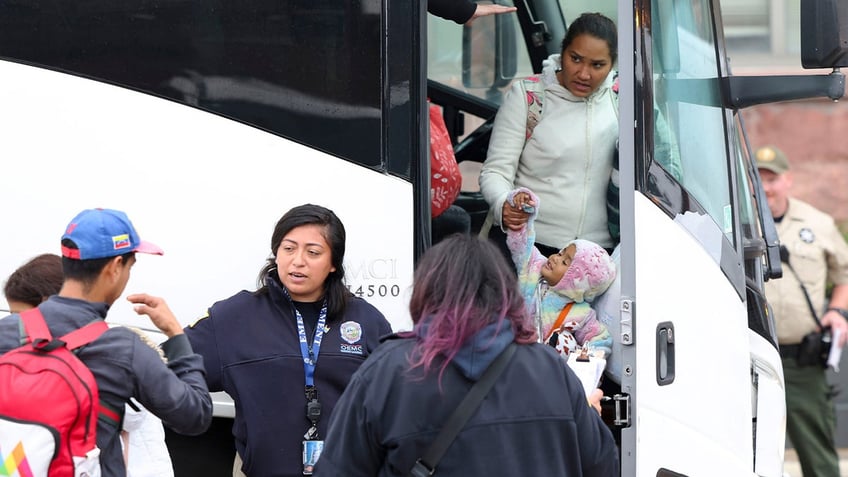 A group of migrants arrive by bus