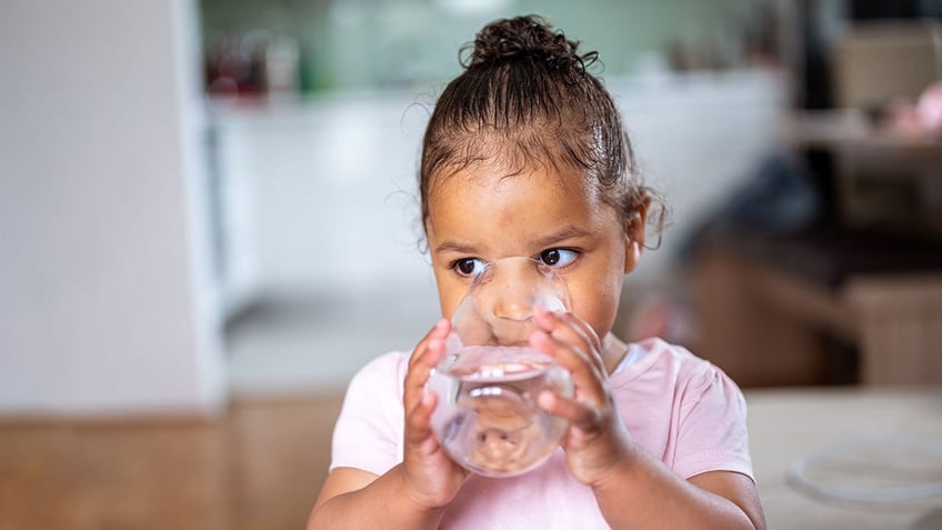 Little girl drinking water from a glass