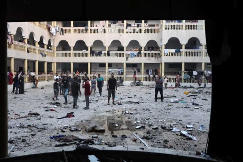 Displaced Palestinians gather in the yard of a school hit by an Israeli strike in Gaza Cit