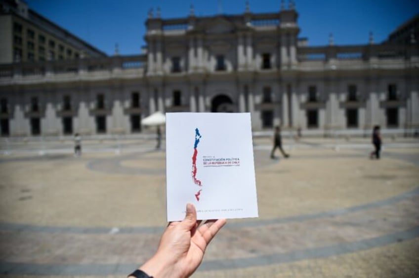 A man holds up a copy of Chile's proposed new Constitution in front of La Moneda Presidential Palace