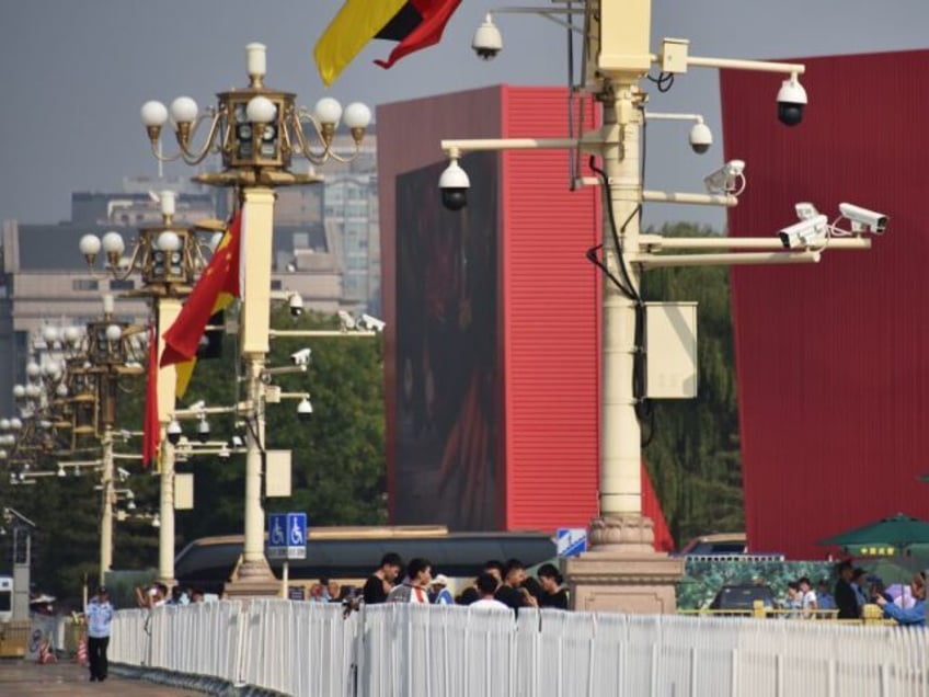 People walk below surveillance cameras in Tiananmen Square in Beijing on September 6, 2019