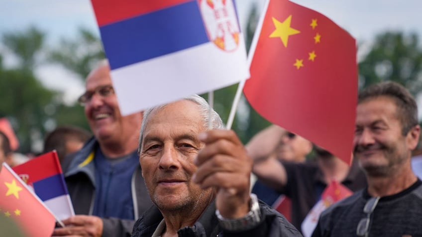 A man waves Chinese and Serbian flags