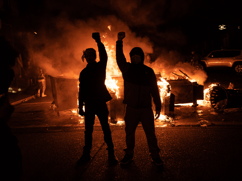 Demonstrators raise their fists as a fire burns in the street after clashes with law enforcement near the Seattle Police Departments East Precinct shortly after midnight on June 8, 2020 in Seattle, Washington. Earlier in the evening, a suspect drove into the crowd of protesters and shot one person, which happened after a day of peaceful protests across the city. Later, police and protesters clashed violently during ongoing Black Lives Matter demonstrations following the death of George Floyd. (Photo by David Ryder/Getty Images)