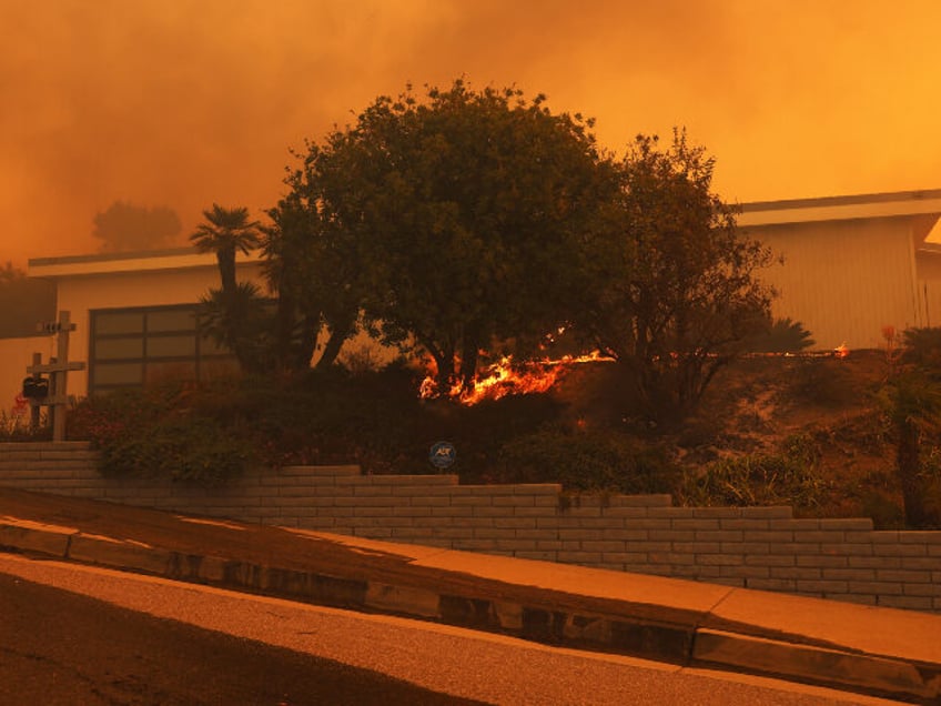 A brush fire burns near homes in Pacific Palisades, California on January 7, 2025. A fast-