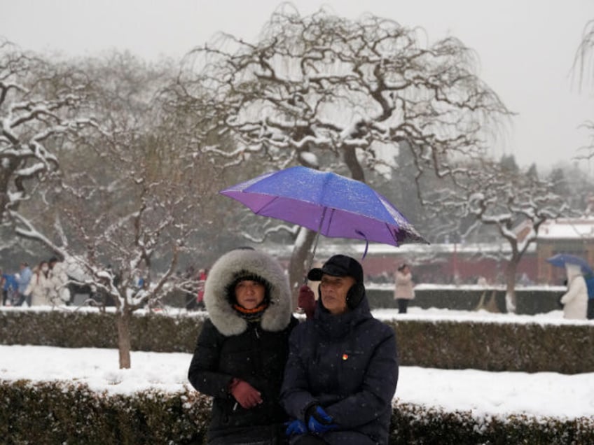 An elderly couple rest in Jingshan Park in Beijing, Wednesday, Dec. 13, 2023. Throngs of people in down parkas and boots climbed a hill that overlooks the Forbidden City this week to jostle with others trying to get a shot of the snow-covered roofs of the former imperial palace.(AP Photo/Ng …