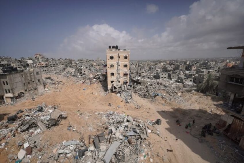 Palestinians stand amid the rubble of houses destroyed by Israeli bombardment in Khan Yuni