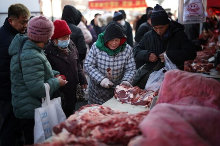 A vendor cuts meat for customers at a market in Shenyang, in China's northeastern Liaoning