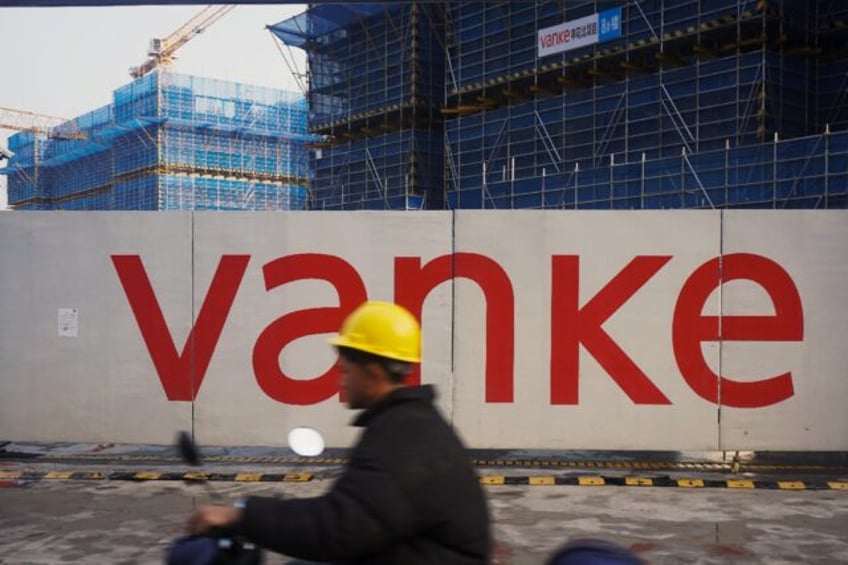 A worker drives past residential buildings under construction by Chinese real estate devel