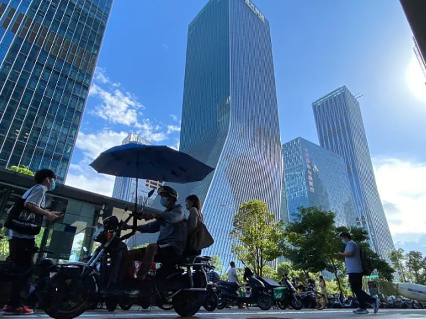 FILE - Residents pass near the headquarters for Evergrande in Shenzhen in southern China, Thursday, Sept. 23, 2021. The troubled Chinese real estate developer with $310 billion of debt is asking investors in one of its bonds to postpone when they will be repaid. (AP Photo/Ng Han Guan, File)