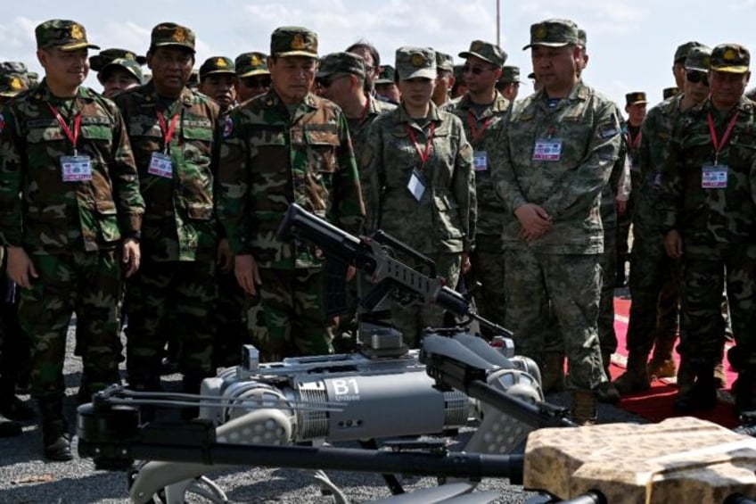 Cambodian armed forces chief Vong Pisen (center L) attends a demonstration of a machine g